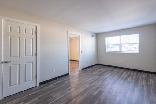 an empty living room with a white door and a window