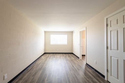 the living room of an empty house with wood floors and a window