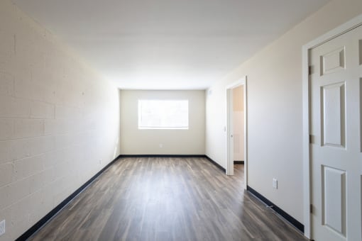 the living room of an empty house with wood floors and a window