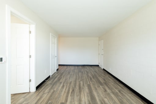 an empty room with white walls and wood floors