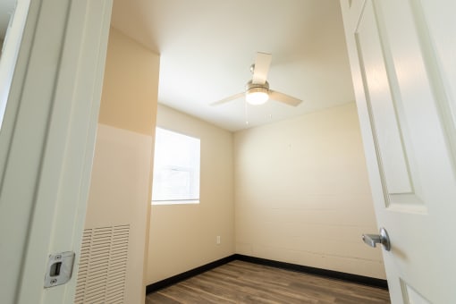 an empty room with a ceiling fan and a window