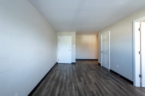 the living room of an empty apartment with wood flooring and a door
