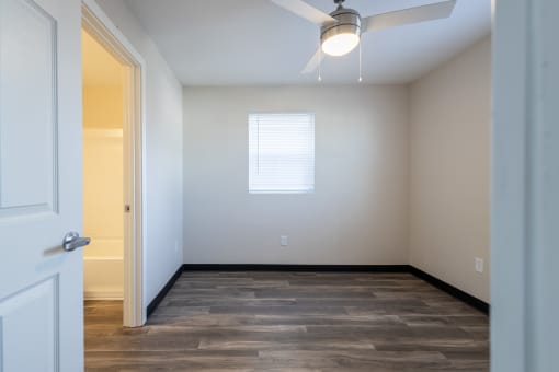 an empty room with wood flooring and a window