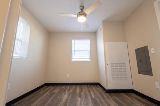 an empty living room with a ceiling fan and a door