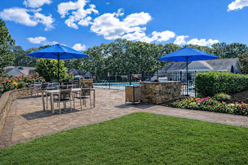 A patio with a table and chairs under blue umbrellas.