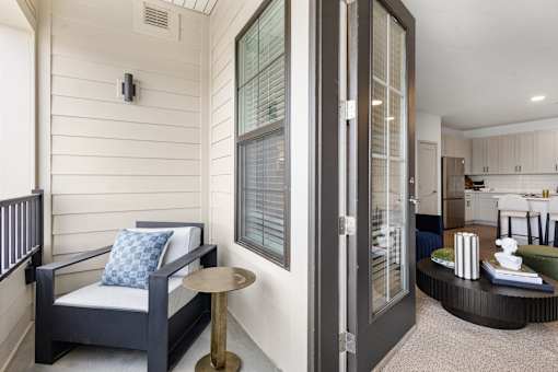 Apartment patio looking toward a glass door that shows a glimpse of the interior room.