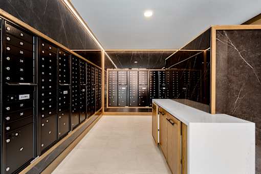 Organized mailroom at Portrait Midtown featuring modern black secure mailboxes and a sleek service counter.