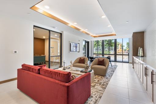 Vibrant apartment community common area featuring stylish lounge seating, mid-century modern accent chairs, a flat-screen TV, and contemporary decor accents perfect for resident gatherings.