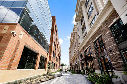 A clean, paved outdoor walkway and landscaped path leading between contemporary buildings at Portrait Midtown apartments.