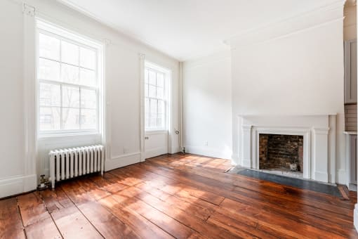 an empty living room with two windows and a fireplace