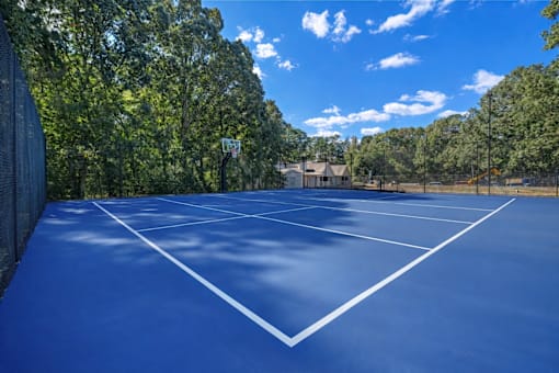 A tennis court surrounded by trees and a fence.