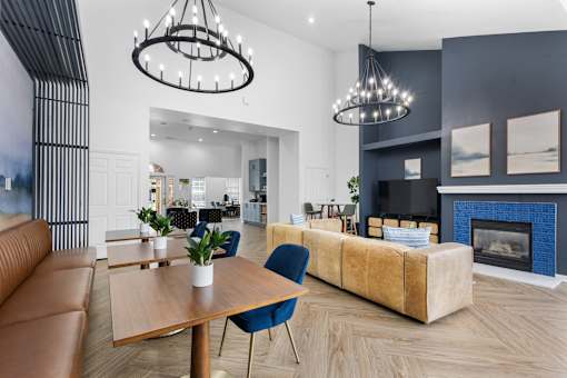 Modern resident clubhouse featuring a cozy fireplace, lounge seating, coworking tables, designer lighting, and upscale finishes at Steeplechase at Shiloh Crossing Apartments in Avon, Indiana.