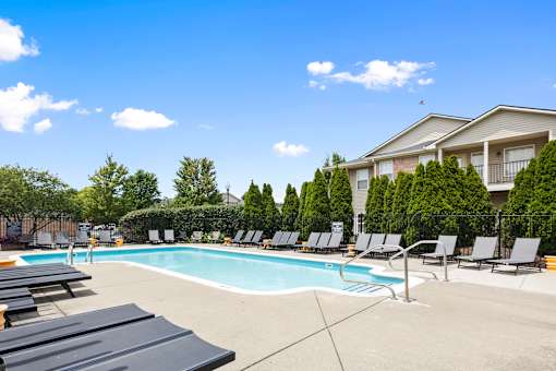 Resort-style outdoor swimming pool surrounded by lounge chairs, a spacious sundeck, and beautifully landscaped grounds at Steeplechase at Shiloh Crossing Apartments in Avon, Indiana.