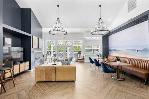 Open-concept resident clubhouse featuring comfortable lounge seating, a fireplace, coworking tables, designer lighting, and views of the outdoor pool at Steeplechase at Shiloh Crossing Apartments in Avon, Indiana.A modern living room with a large window overlooking the water.
