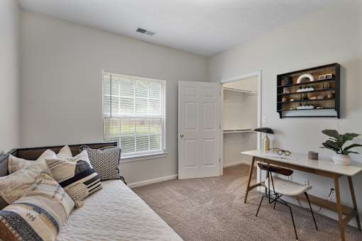 Bright open-concept living room with plush carpeting, large window, and patio access at Steeplechase at Shiloh Crossing Apartments in Avon, Indiana.