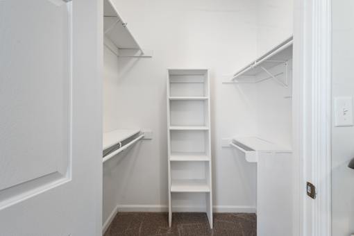 Spacious walk-in closet featuring built-in shelving, double hanging rods, and ample storage space at Steeplechase at Shiloh Crossing Apartments in Avon, Indiana.