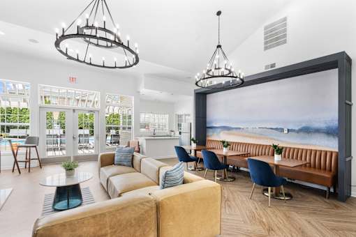 Modern resident clubhouse featuring comfortable lounge seating, coworking tables, vaulted ceilings, and views of the resort-style pool at Steeplechase at Shiloh Crossing Apartments in Avon, Indiana.