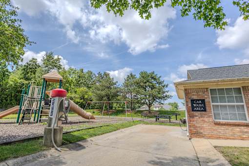 Community playground with slides and swings, picnic area, and convenient resident car wash station at Steeplechase at Shiloh Crossing Apartments in Avon, Indiana.