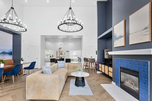 Spacious resident clubhouse featuring a modern fireplace, comfortable lounge seating, coworking tables, designer chandeliers, and upscale community amenities at Steeplechase at Shiloh Crossing Apartments in Avon, Indiana.