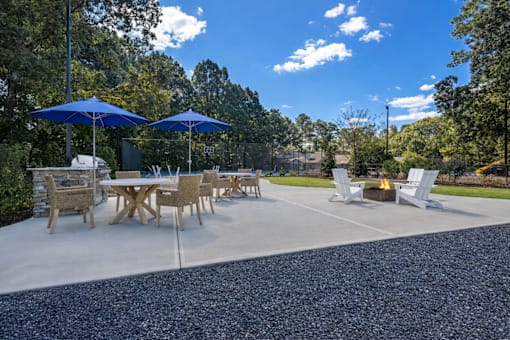 A patio with a table and chairs under blue umbrellas.