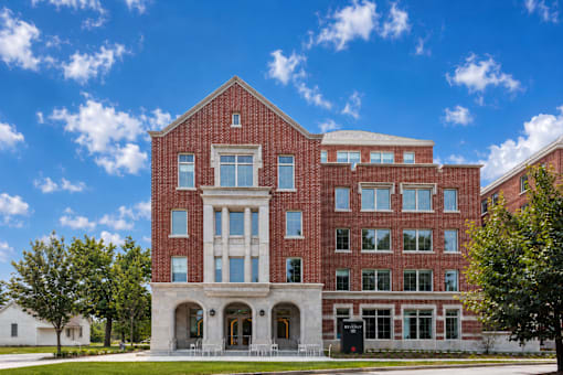 A red brick building with a white entrance and a tree in front.