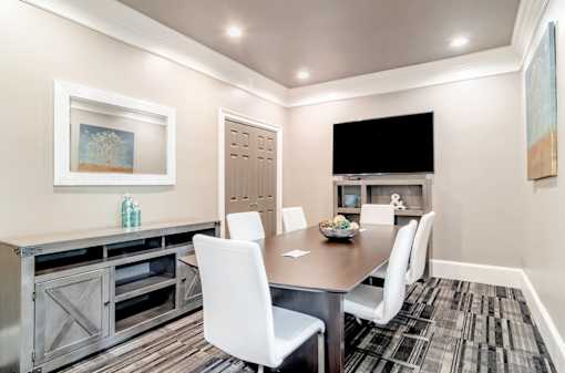 Modern resident conference room with sleek furnishings, a large table, and a mounted TV at Village at Almand Creek apartments in Conyers, GA. Perfect for meetings and remote work.