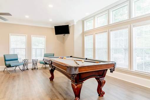 Stylish resident game room with a pool table, lounge seating, and large windows at Village at Almand Creek apartments in Conyers, GA. Perfect for socializing and relaxation.