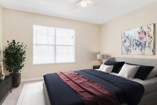 Spacious bedroom with large window, natural light, and modern decor at Village at Almand Creek apartments in Conyers, GA. Features plush carpeting and contemporary design.