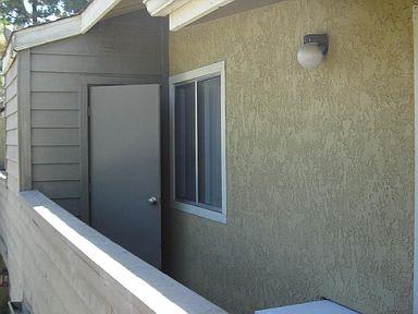 A picture of a 2nd story apartment balcony with a storage room door ajar and a porch light that is off.