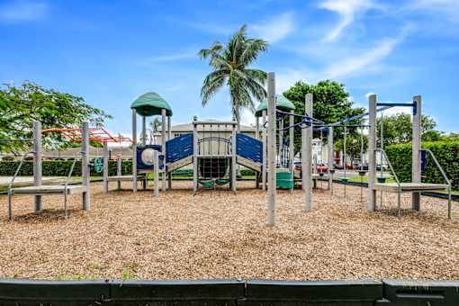 A playground with a slide, swings, and a green roofed structure.