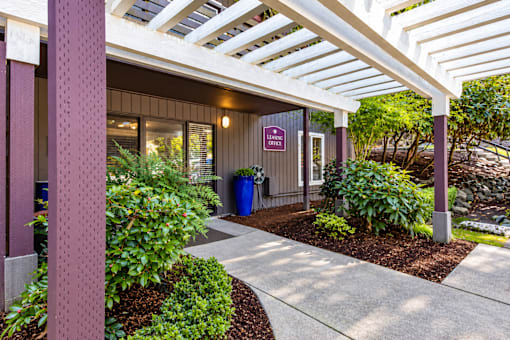A building with a purple sign that says "EXIT" is surrounded by plants and has a white canopy above it.