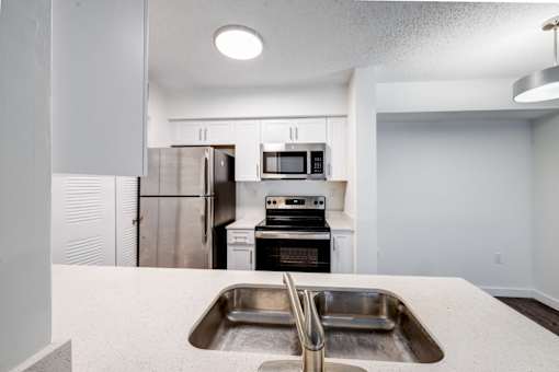 A kitchen with a sink, stove, and refrigerator.