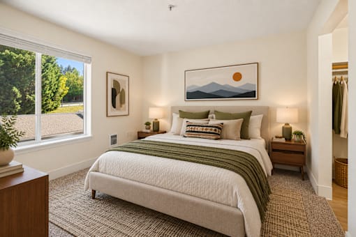 A bedroom with a large bed and a painting of a sunset on the wall.