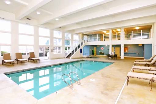 A large indoor swimming pool with lounge chairs and a staircase.