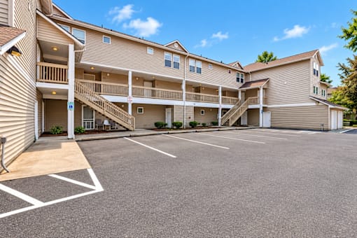 A large, multi-story apartment complex with a parking lot in front.