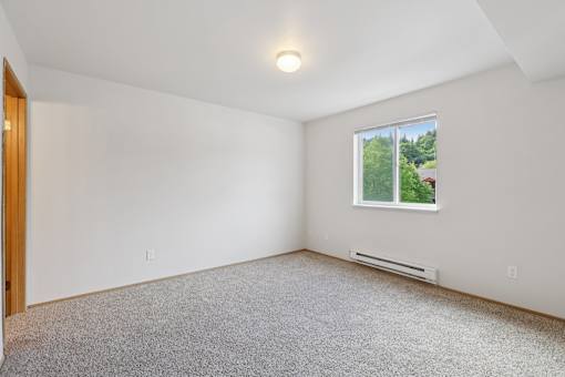 A room with a window and a carpeted floor.