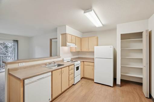 A kitchen with white appliances and wooden cabinets.at Vintage at Vancouver, Vancouver, WA 98662