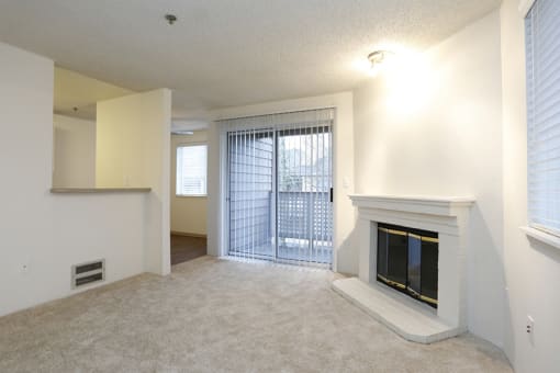 Apartments for Rent in Des Moines - Marina Club - Living Room With Carpet Flooring, a Fireplace, and a Sliding Glass Door Leading to the Balcony