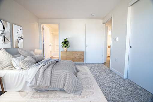 A bedroom with a bed, pillows, a plant, and a painting on the wall at Troutdale Terrace, Troutdale, Oregon, 97060