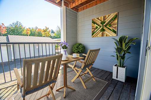 A wooden chair and table set up on a porch at Troutdale Terrace, Troutdale, OR, 97060