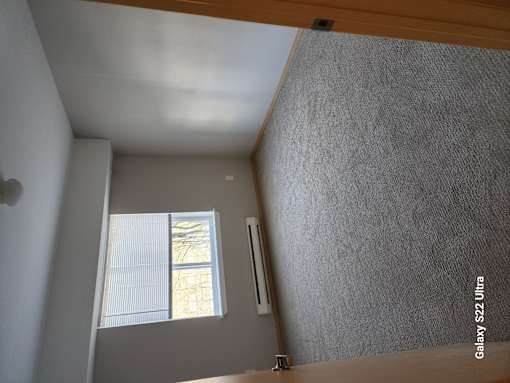 A room with a window and a wall with a textured surface.