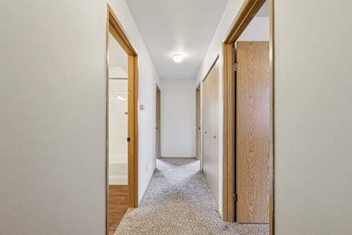 A hallway with a carpeted floor and white walls.