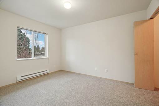 A room with a window, a door, and a carpeted floor.at Vintage at Vancouver, Vancouver