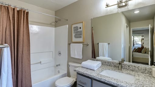 Pet-friendly Apartments in Hayward, CA - Austin Commons - Bathroom with Vanity Mirror, Bathroom Shower, and Wall Art