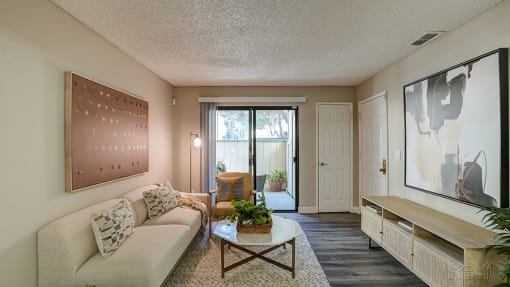 Apartments for Rent in Hayward CA - Austin Commons - Living Room with Sofa, Chair, Table, TV Stand, and Sliding Glass Door.