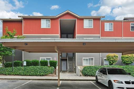 A red and grey building with a white car parked in front.
