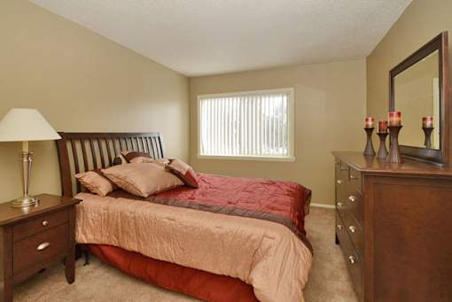 A bedroom with a bed, nightstand, and dresser.