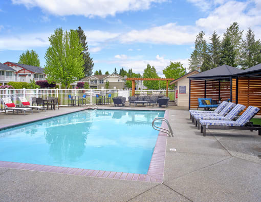 Two BR Apartments in Dupont, WA - Clock Tower Village - Outdoor Swimming Pool with Lounge Chairs, Shade Gazebos, and Lush Greenery