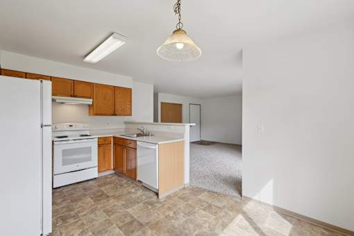 A kitchen with a white refrigerator, wooden cabinets, and a tiled floor.