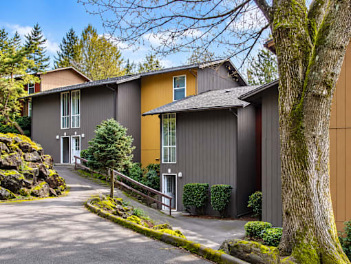 A building with a grey and yellow exterior is surrounded by greenery.
